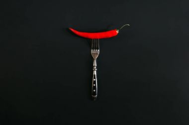red hot chili pepper on fork on black clipart