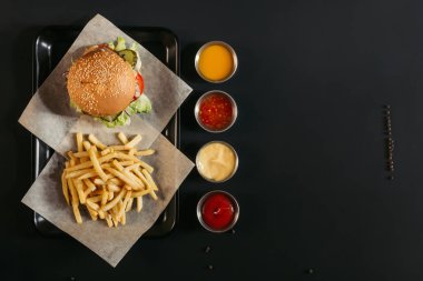 tepsi ve siyah çeşitli soslar Fransız kızartması ile lezzetli burger Üstten Görünüm   
