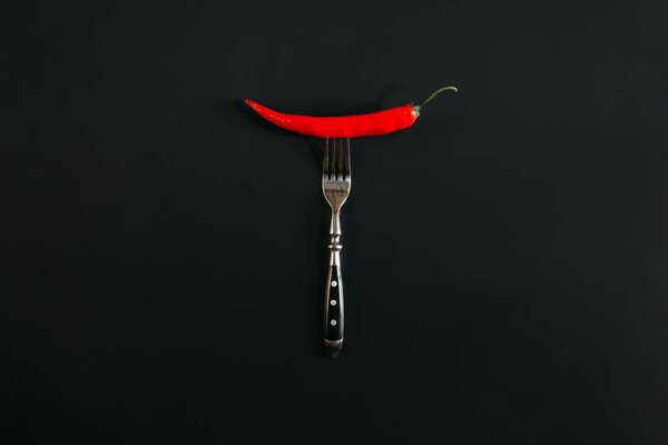 красный острый перец чили на вилке на черном
