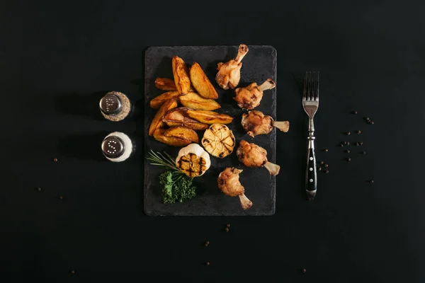 在黑色石板板上的美味烤土豆鸡肉和烤大蒜的顶级视图 — 图库照片