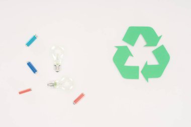 top view of light bulbs and batteries with recycle sign on white clipart