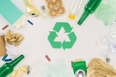 top view of various types of trash surrounding recycle sign on white clipart