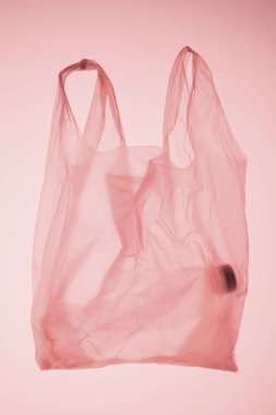 pastel pembe tonda ışık altında içinde şişeyle şeffaf plastik torba
