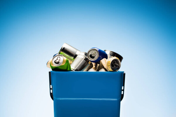 various metal cans in trash bin on blue