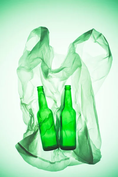 緑のトーンの光の下でガラスびんとくしゃくしゃのビニール袋  — 無料ストックフォト