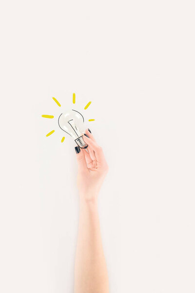 обрезанный снимок женщины, держащей лампочку с нарисованным стеклом и световыми лучами
