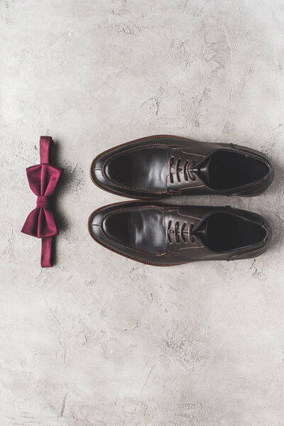 top view of pair of shoes and bow tie for wedding on gray surface
