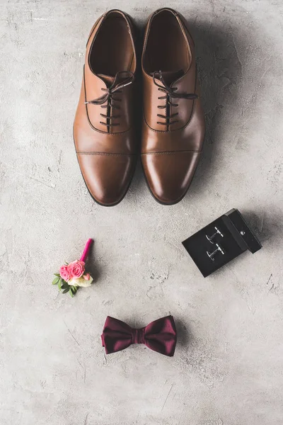 灰色の表面に茶色の靴 カフスボタン 蝶ネクタイ ブートニアのトップ ビュー — ストック写真