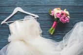 Draufsicht auf Brautstrauß und weißes Kleid auf dunkelblauer Tischplatte