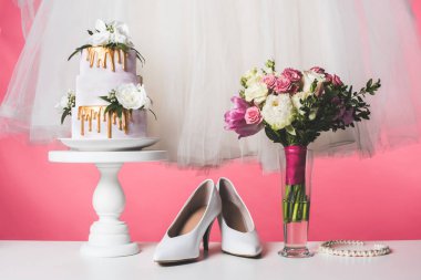 wedding cake on cake stand with white dress and bouquet isolated on pink clipart