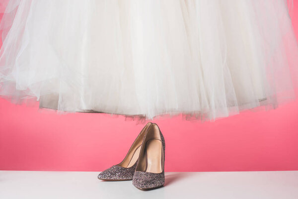 pair of shoes and wedding dress isolated on pink