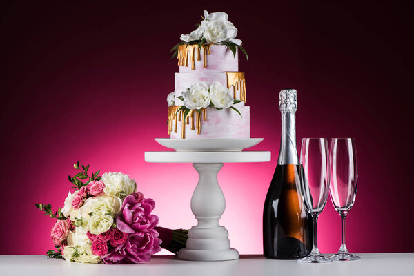 wedding bouquet, cake and champagne on pink