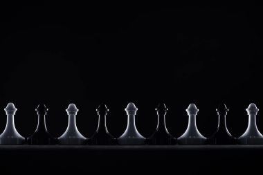 silhouettes of black and white chess pawns isolated on black, business concept clipart