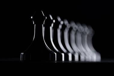 silhouettes of row of chess figures isolated on black, business concept clipart