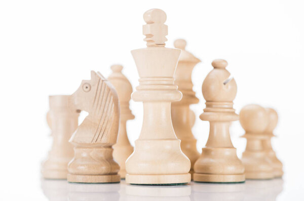 белый деревянный шахматный король с рыцарем и слоном по бокам на белом
 