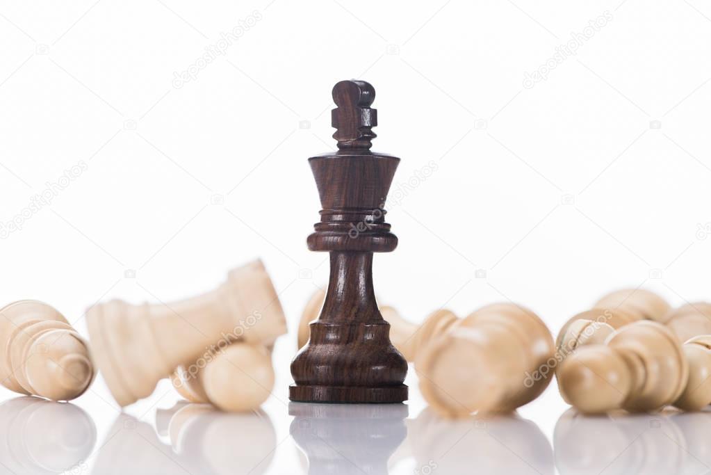 black chess king with fallen white pawns on white, business concept