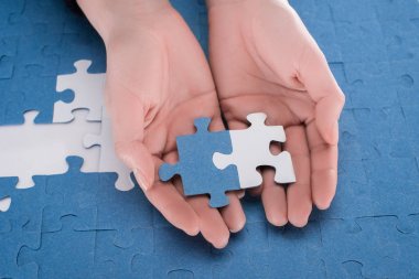 cropped image of businesswoman holding assembled white and blue puzzles, business concept clipart