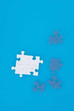 top view of white and blue puzzles isolated on blue, business concept clipart