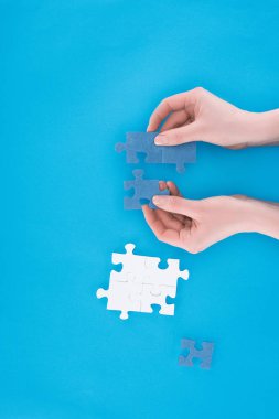 cropped image of businesswoman assembling blue puzzles isolated on blue, business concept clipart