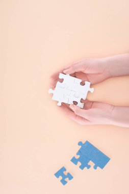cropped image of businesswoman holding assembled puzzles piece in hands isolated on beige, business concept clipart