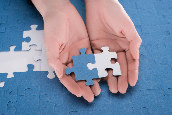 cropped image of businesswoman holding assembled white and blue puzzles, business concept