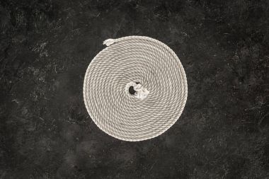 top view of white nautical rope arranged in circle on dark concrete tabletop clipart