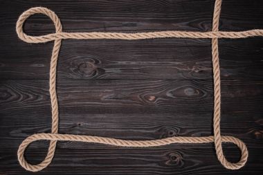 top view of brown nautical rope on dark wooden surface clipart