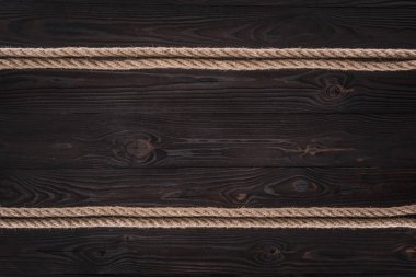top view of arrangement of brown nautical ropes on dark wooden tabletop clipart