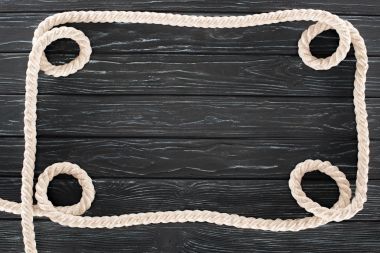 top view of white nautical rope on dark wooden surface clipart