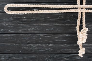 top view of white nautical rope with knots on dark wooden tabletop clipart
