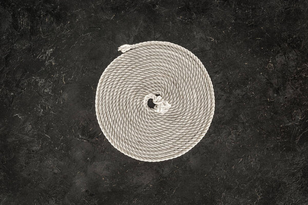 top view of white nautical rope arranged in circle on dark concrete tabletop