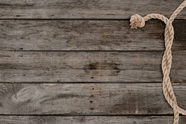 вид сверху на морскую верёвку с узлом на гранжевой деревянной поверхности
