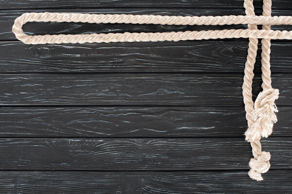 top view of white nautical rope with knots on dark wooden tabletop