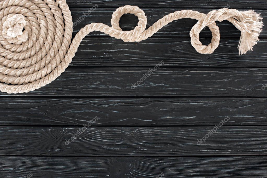 vista dall'alto della corda marina bianca disposta in cerchio su un tavolo di legno scuro
