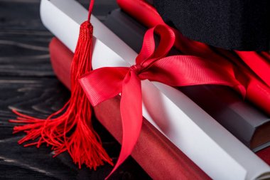 Mezuniyet şapka ve diploma kitap yığını üzerinde kırmızı kurdele ile