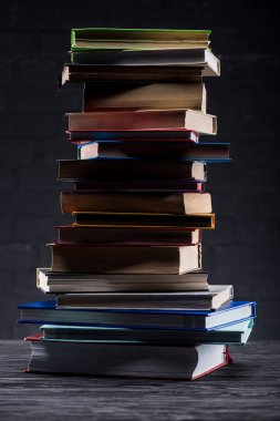 High stack of books on dark wooden background clipart
