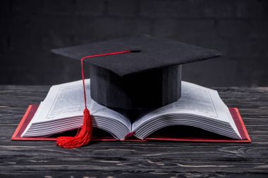 Ahşap masa üzerinde mezuniyet kap ile açık kitap
