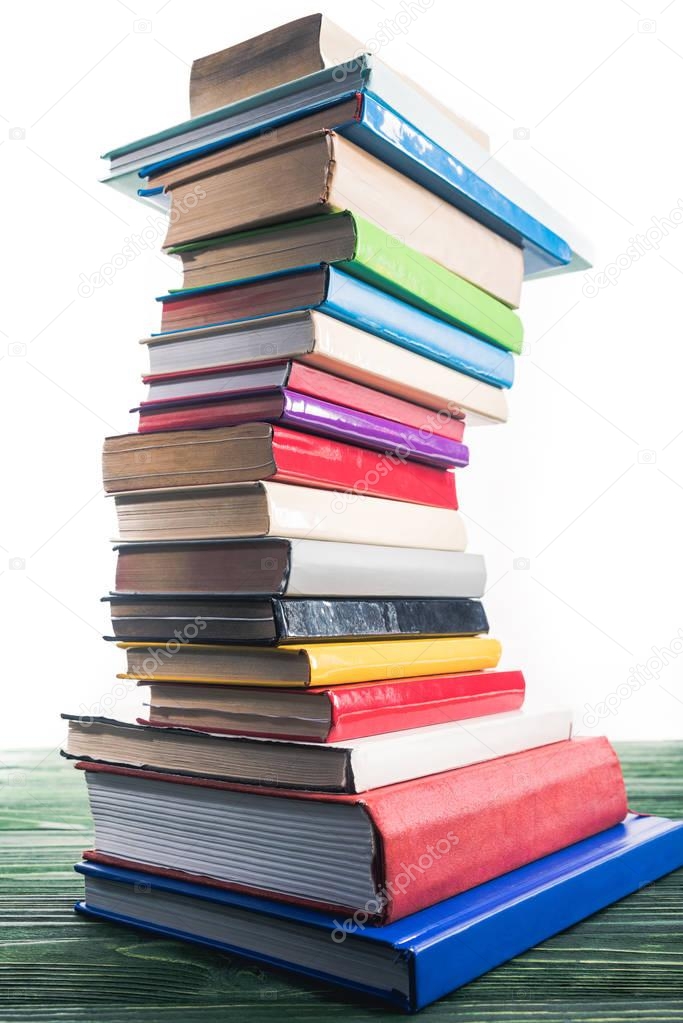 High bent tower of stacked books on wooden table