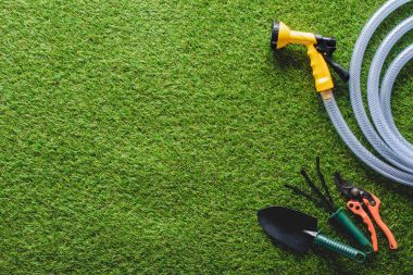 top view of hosepipe, hand rake, spade and secateurs on grass clipart