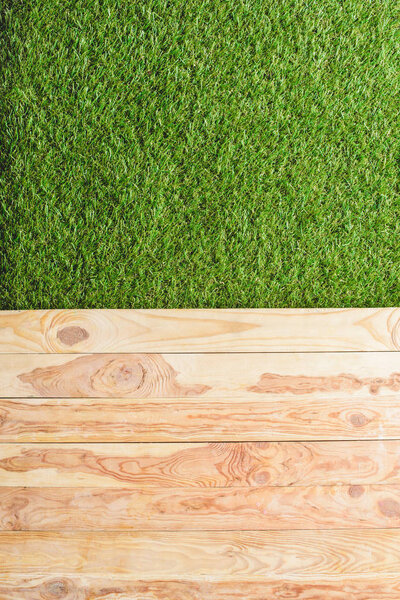 top view of green lawn and wooden planks background 