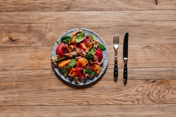 салат для гурманов с мидиями, овощами и хамоном на деревянном столе
