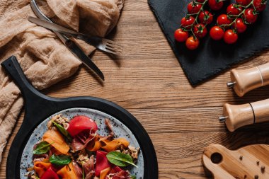 Midye, sebze ve jamon, çatal bıçak ve ahşap masa üzerinde taze domates salatası