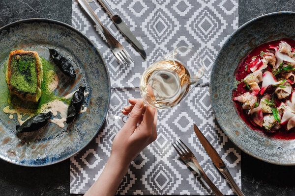 top view of gourmet fried zander, ceviche with dorado and person holding glass of wine 