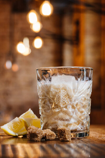 close-up view of glass with cream alcohol cocktail, lemon and brown sugar on wooden table