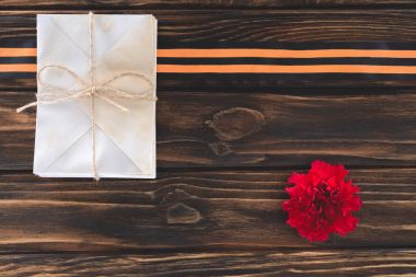top view of box wrapped by string, carnation and st. george ribbon on wooden planks clipart