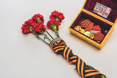 closeup shot of flowers wrapped by st. george ribbon and box with medals, victory day concept clipart