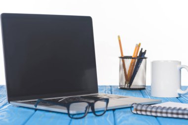 closeup shot of eyeglasses on laptop, textbook, organizer with stationery and mug  clipart