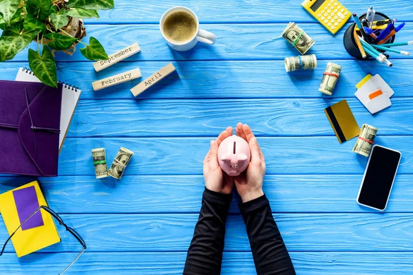 Kleines Sparschwein Der Hand Auf Blauem Holztisch Mit Geld — Stockfoto