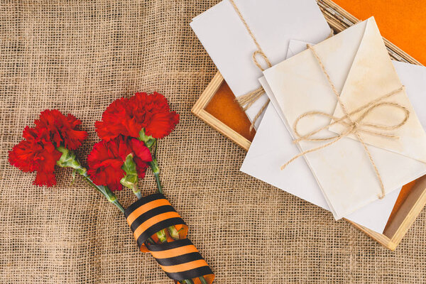 top view of stacks of letters on photo frame and carnations wrapped by st. george ribbon 