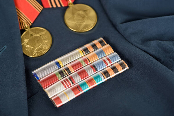 closeup shot of different medals on navy blue jacket, victory day concept 